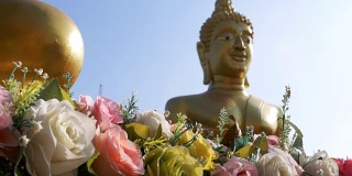 鲜花在一个大的背景金佛在泰国的寺庙。芭堤雅