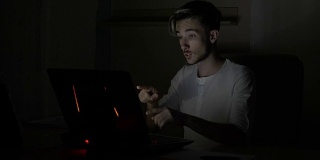年轻貌美的男学生在家里一间暗室里视频聊天，并对着摄像头挥手