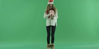 迷人的年轻女子在圣诞帽看她的圣诞礼物，色度键的背景