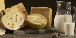 不同种类的奶酪和牛奶罐放在木桌上