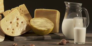 不同种类的奶酪和牛奶罐放在木桌上