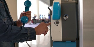 在国际机场内使用公用固定电话的亚洲人。