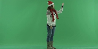 迷人的年轻女子戴着圣诞帽，使用虚拟触摸屏技术，背景色键