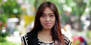 美丽的东南亚女人在镜头前微笑的肖像公园与三种色调