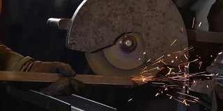 在工厂里，工人正在用圆盘抛光机打磨金属梁的边缘