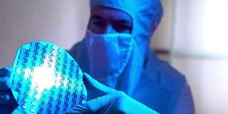洁净室技术人员正在检查一个硅片微芯片磁盘