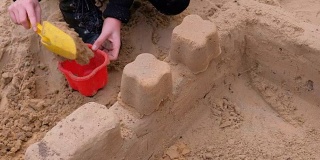 小女孩在院子里玩沙子。建造一座沙堡