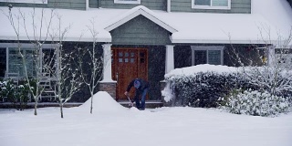 在家门口铲雪的男人