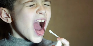 男孩用医用喷雾喷自己的嘴，防止过敏