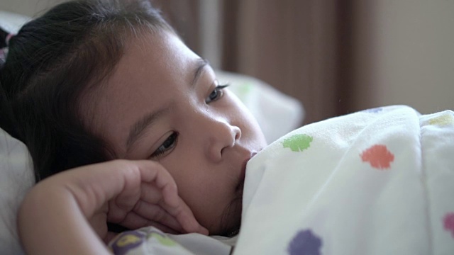 生病的亚洲小女孩躺在医院的床上的特写慢动作拍摄