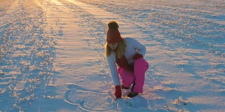 冬日日落的女人在雪地上用手画心4k
