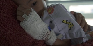 在慢镜头中，生病的亚洲女孩用手裹着绷带拥抱她的母亲