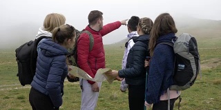 专业导游为年轻游客讲解路线，背包阅读纸质地图，带领登山路线