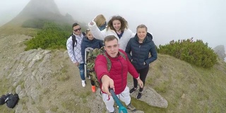 一群欢呼的青少年朋友站在山顶上视频自拍，分享他们的旅行冒险