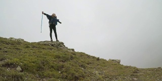 自由和幸福的观念与登山者快乐的女人登上山顶，举起手臂