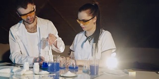 两名技术人员或科学家在化学实验室用烧杯里的彩色溶液做实验