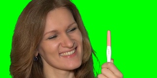 快乐的女人脸上显示怀孕测试阳性和大拇指向上的手势