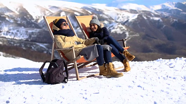 冬日里，两个女孩在躺椅上晒太阳