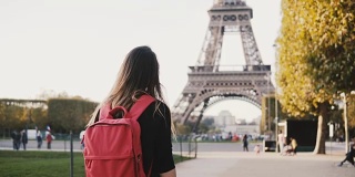 年轻快乐的女人背着双肩包独自走在埃菲尔铁塔和火星champs附近，法国巴黎