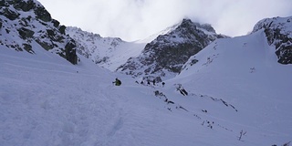 在寒冷的阳光明媚的天气里，滑雪游览覆盖在雪中的岩石山脉景观