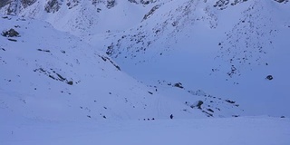 在寒冷的阳光明媚的天气里，滑雪游览覆盖在雪中的岩石山脉景观