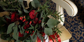 美丽的婚礼组成组成的蜡烛和美丽的红玫瑰花束和牡丹在红色丝带躺在复古扶手椅。