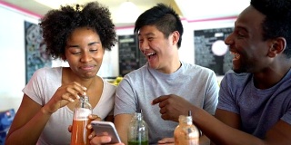 一群快乐的朋友在果汁吧看智能手机上的照片