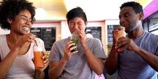Multi ethnic group of friends enjoying a juice at a restaurant laughing and having fun