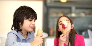哥哥和姐姐在冰淇淋店享受着冰淇淋，看起来很开心，谈笑风生