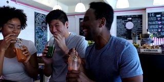 亚洲和黑人朋友在果汁吧与瓶装果汁祝酒，大笑和玩得很开心