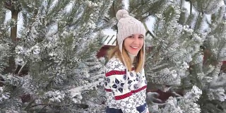 微笑的女人走在冬天的雪中沿着小巷松树旋转