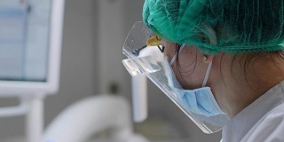 戴医用口罩和橡胶手套的妇女拿着软管并将其插入病人口中