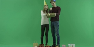 年轻夫妇向相机展示圣诞礼盒，背景上的色度键