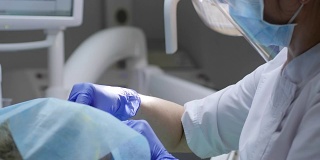 医务人员在牙科诊所用牙镜检查口腔疾病，脸上贴有消毒餐巾