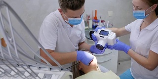 医生用特殊的牙科相机在办公室里用现代化的设备拍摄女病人的口腔