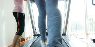 健身女性在跑步机上与健身教练在健身房，有氧训练的概念