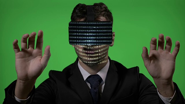 西装革履的男工程师使用未来虚拟现实技术在绿色屏幕上输入和检查区块链数据