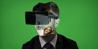 一名男子戴着虚拟现实眼镜在绿色屏幕上滚动他的社交媒体账户
