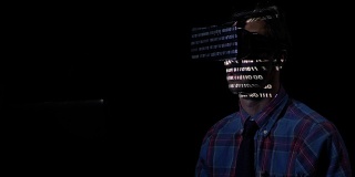 未来的计算机程序员坐在一间黑屋子里，在家里试着戴上VR眼镜，检查他的网站的顺序二进制代码