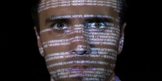 一个年轻的IT程序员网络工作者的肖像，男性工作的反病毒程序，而代码投射在他的脸上
