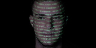 运行着绿色程序代码的人脸上折射着一个年轻冷静的男性电脑黑客