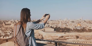 女游客拍摄耶路撒冷老城的照片。带着背包微笑的漂亮白种女旅行者。以色列。4 k