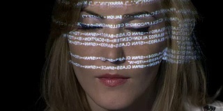 近距离的人工智能IT女性编程二进制代码在未来的全息显示上反映在她的脸上