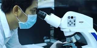 在实验室用显微镜做实验的科学家