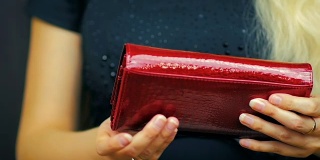 一个年轻女孩的特写关闭一个红色钱包，其中有现金和信用卡在慢动作