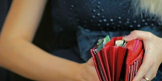 慢镜头:年轻的金发女郎打开一个红色皮夹，里面有现金和信用卡