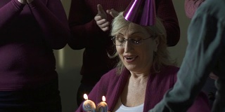 快乐的女人吹灭蛋糕上的蜡烛，许愿，90岁生日，玩得开心