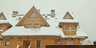 一个木制的高地人的房子和飘落的雪