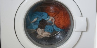 洗衣机门里面有可旋转的衣物。集中在脏衣服的中心和洗衣机的框架上