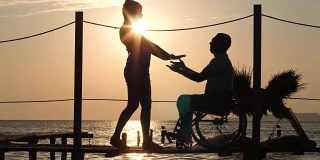 阳光下残障男女的剪影，在海滨浪漫的相遇